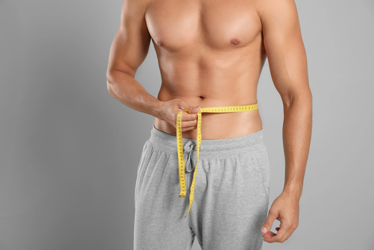Man measuring waist with a tape, representing GLP-1 weight loss treatments and the science behind body measurements for weight management.