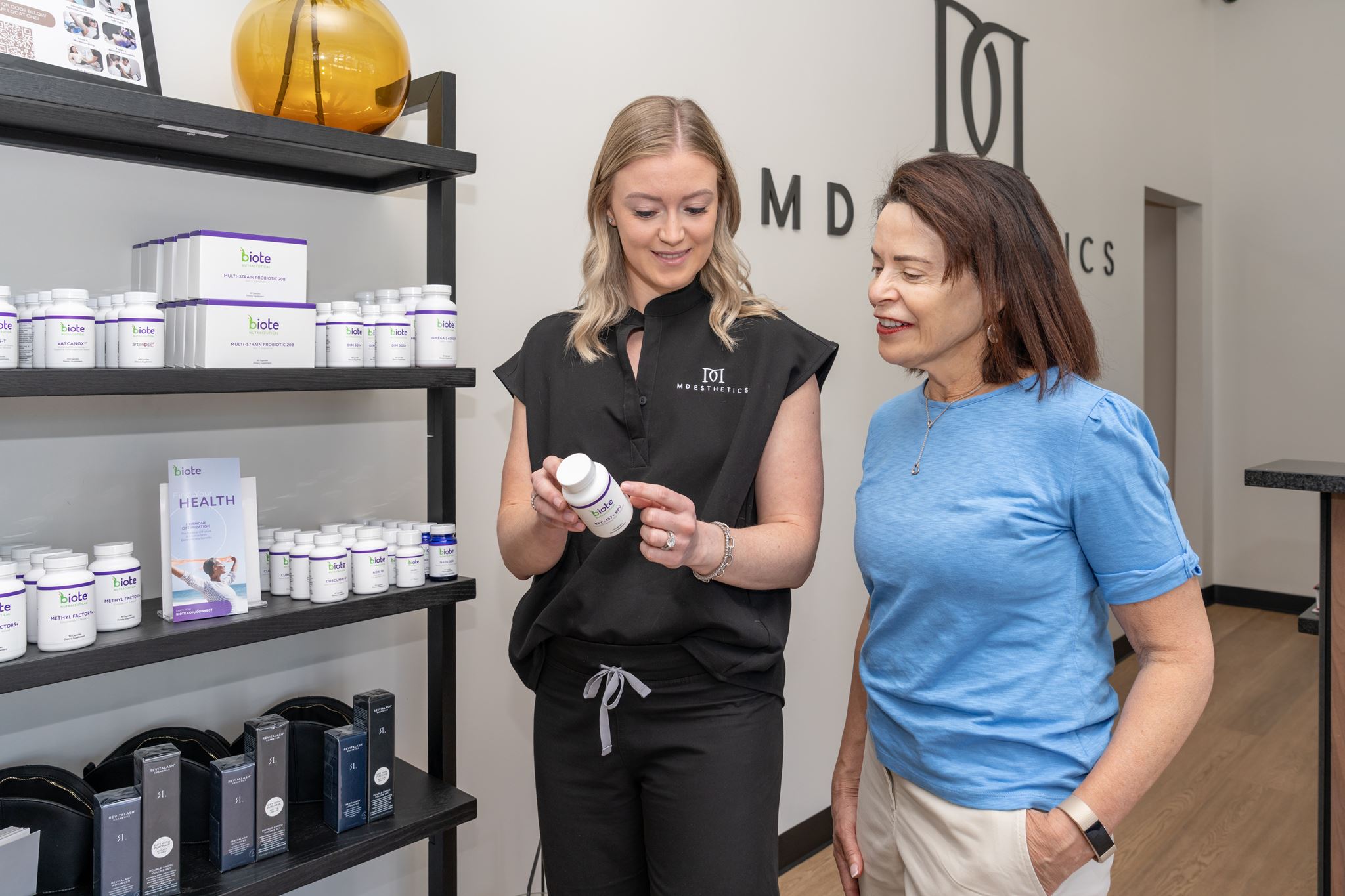 An MD Esthetics provider showing Biote supplements to a patient in the clinic